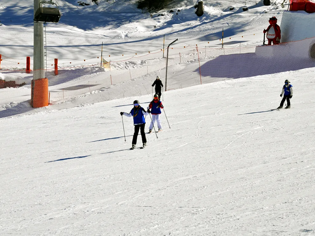 Skifahrende auf der Piste neben einer Liftstütze.